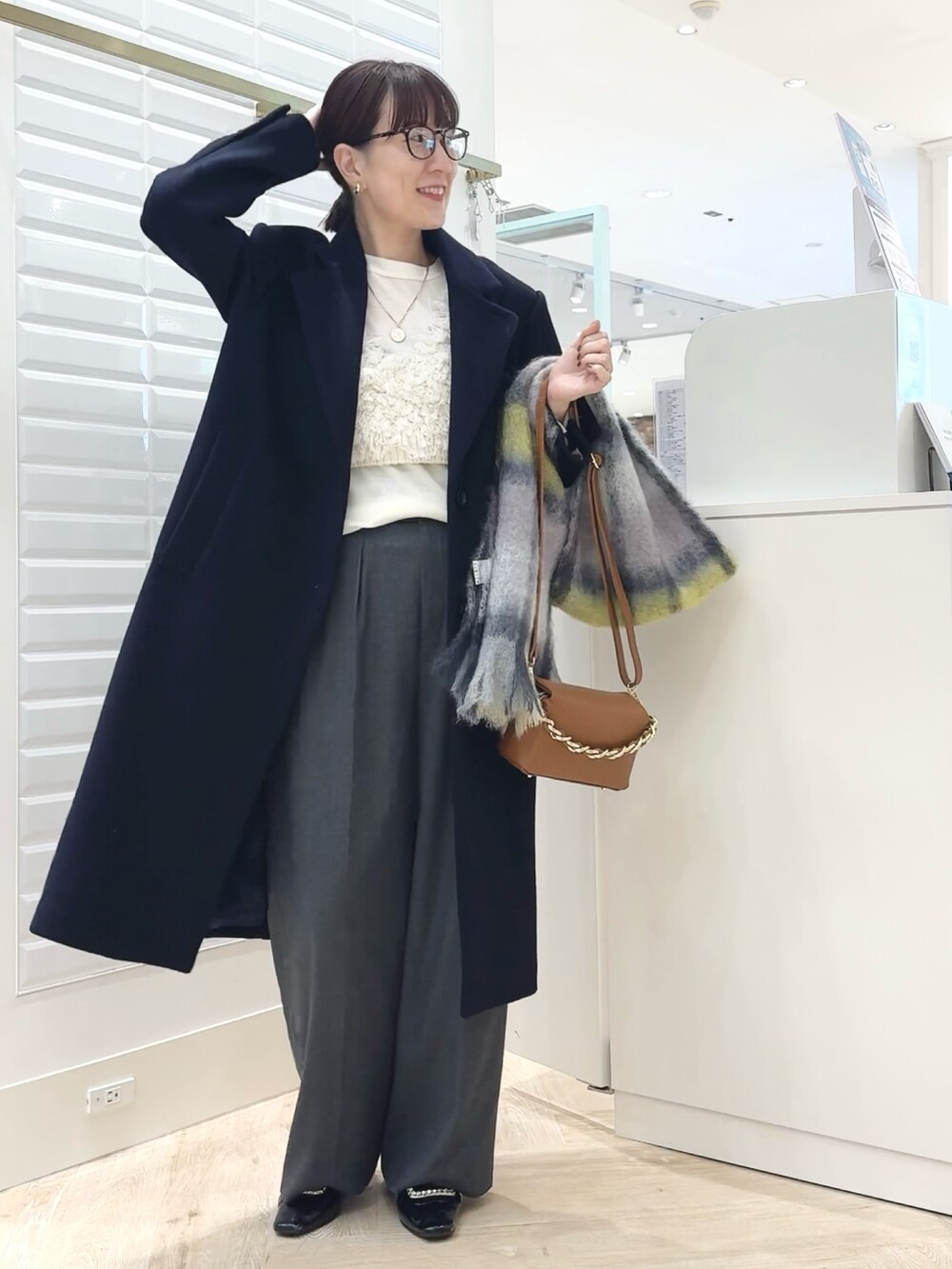 グレー系のその他パンツ、ブルー系のチェスターコート、ホワイト系のベストを着用したレディースの秋コーディネートの7枚目の写真