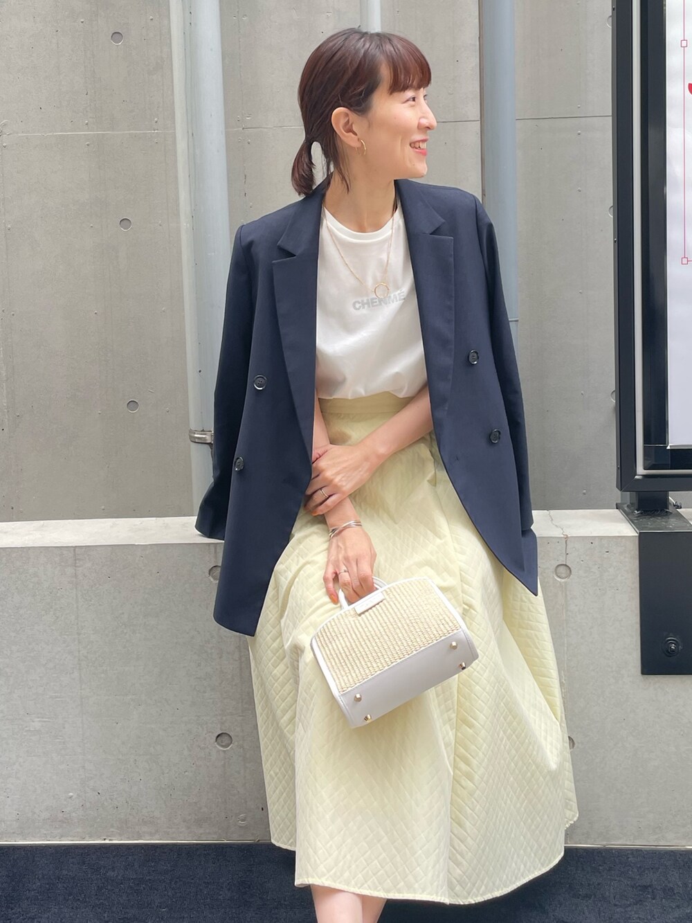 ブルー系のテーラードジャケット、ホワイト系のトートバッグ、イエロー系のスカートを着用したレディースの春コーディネートの2枚目の写真