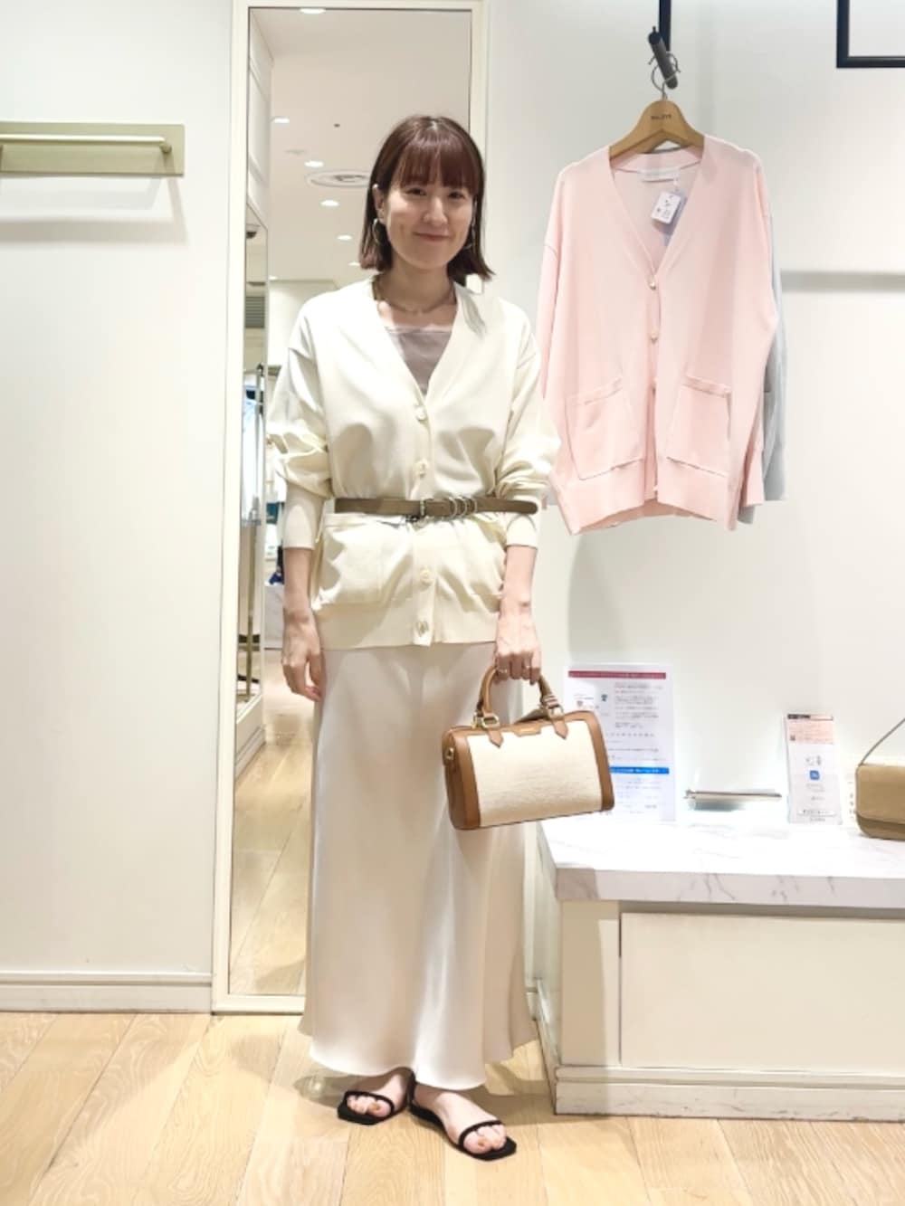 ベージュ系のタンクトップ、ホワイト系のスカート、ブラウン系のボストンバッグを着用したレディースの春コーディネートの3枚目の写真