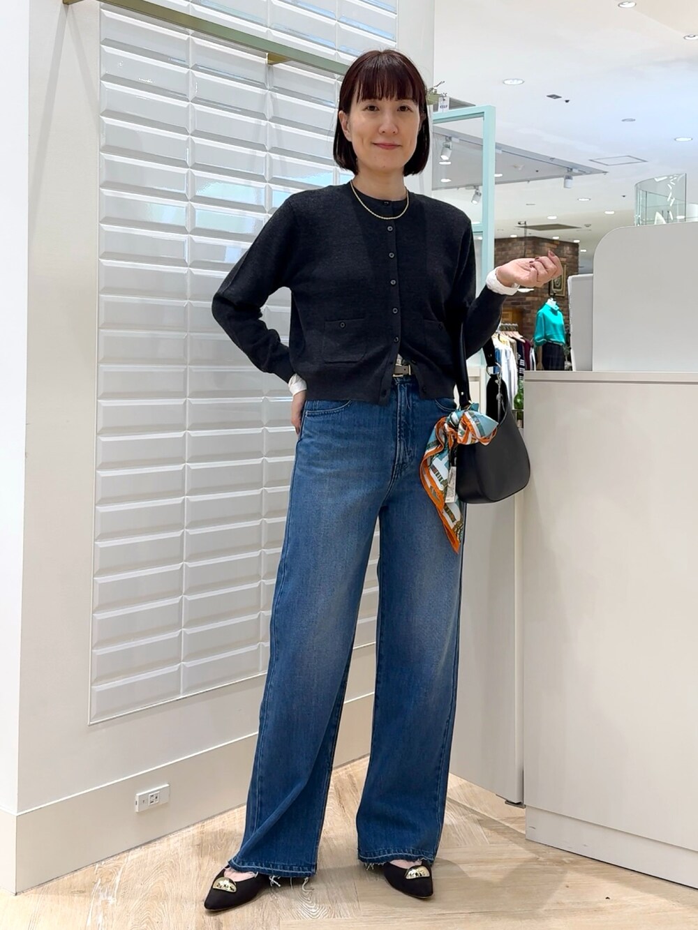 ブルー系のデニムパンツ、グレー系のカーディガン/ボレロ、ホワイト系のTシャツ/カットソーを着用したレディースの秋コーディネートの5枚目の写真