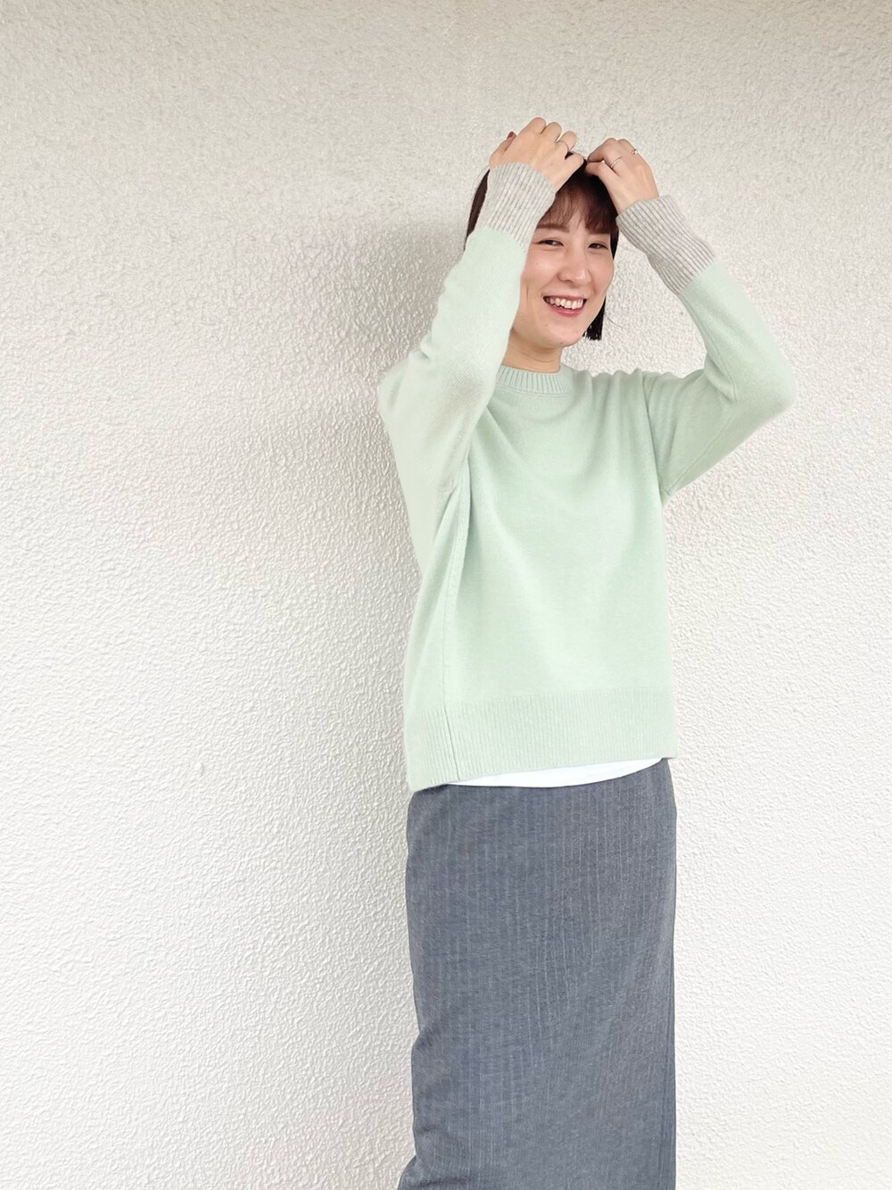 ベージュ系のトートバッグ、グレー系のスカート、グリーン系のニット/セーターを着用したレディースの冬コーディネートの2枚目の写真