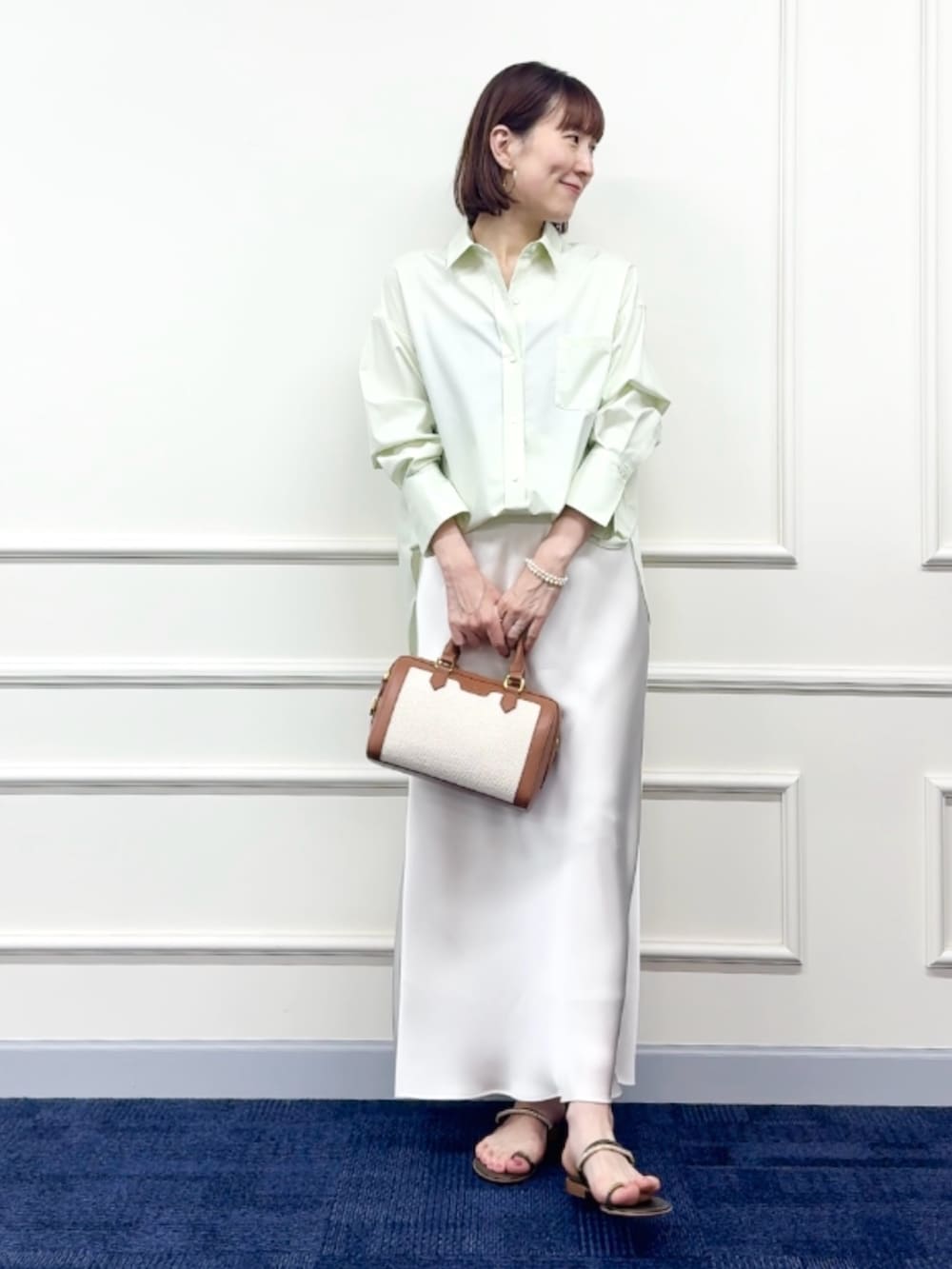 ブラウン系のボストンバッグ、ホワイト系のスカート、グリーン系のシャツ/ブラウスを着用したレディースの冬コーディネートの3枚目の写真