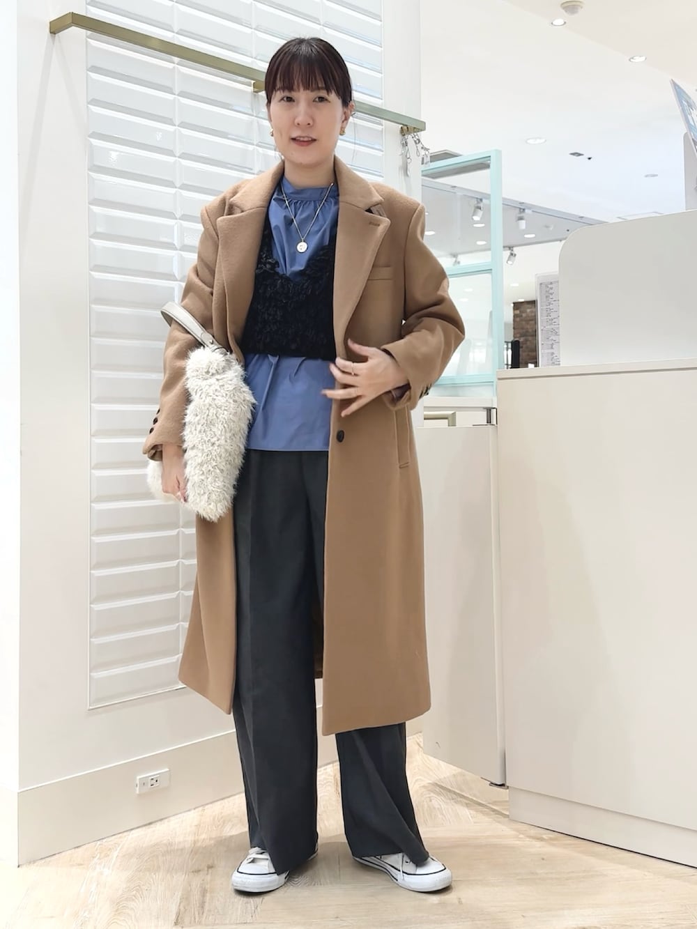 グレー系のベスト、ブルー系のシャツ/ブラウス、ホワイト系のショルダーバッグを着用したレディースの秋コーディネートの5枚目の写真