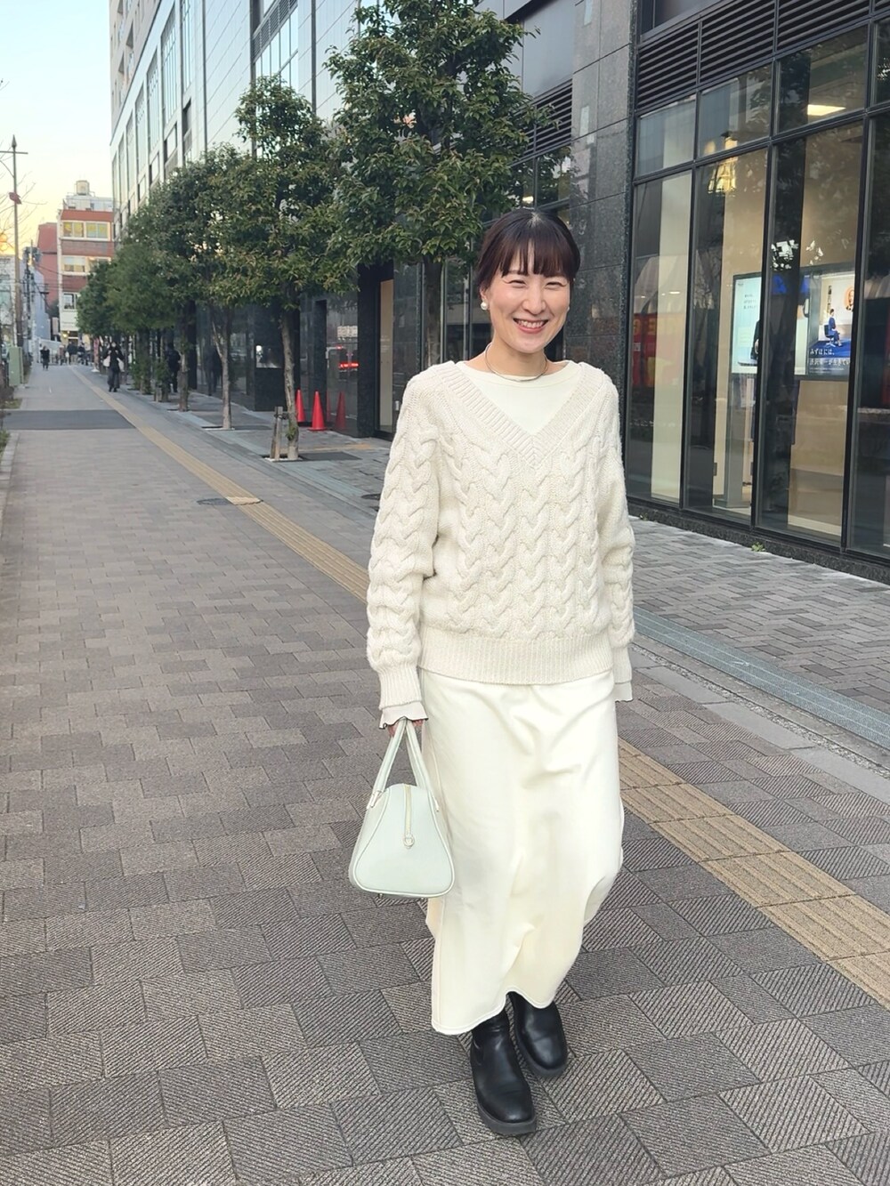 ホワイト系のニット/セーター、ホワイト系のTシャツ/カットソー、グリーン系のショルダーバッグを着用したレディースの冬コーディネートの6枚目の写真
