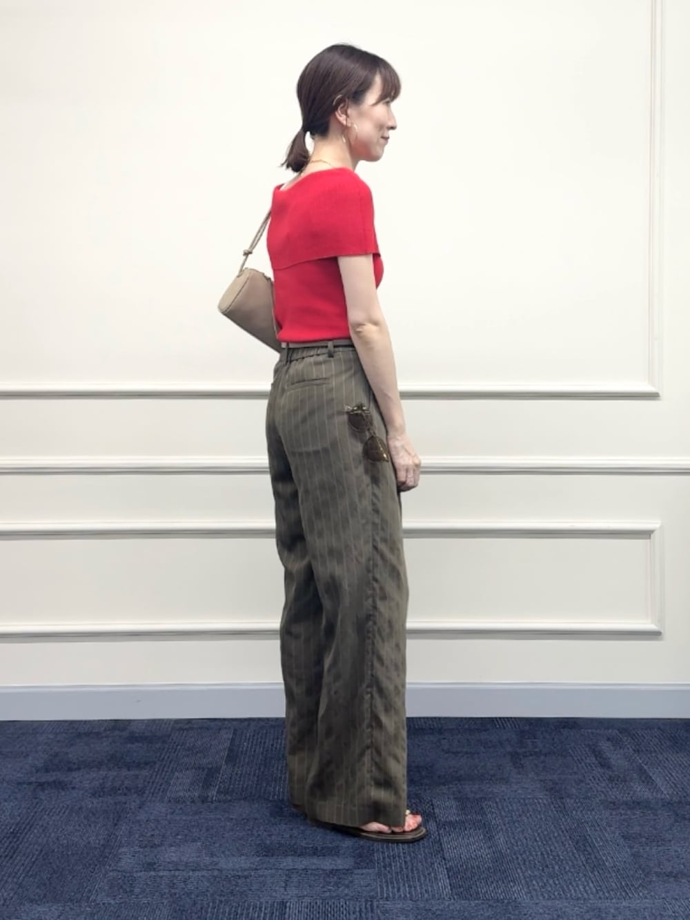レッド系のニット/セーター、グリーン系のその他パンツ、ベージュ系のショルダーバッグを着用したレディースの夏コーディネートの4枚目の写真