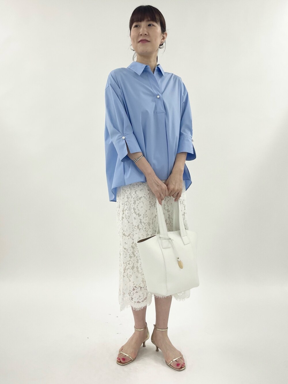 ゴールド系のサンダル、ホワイト系のスカート、ホワイト系のトートバッグを着用したレディースの春コーディネートの4枚目の写真