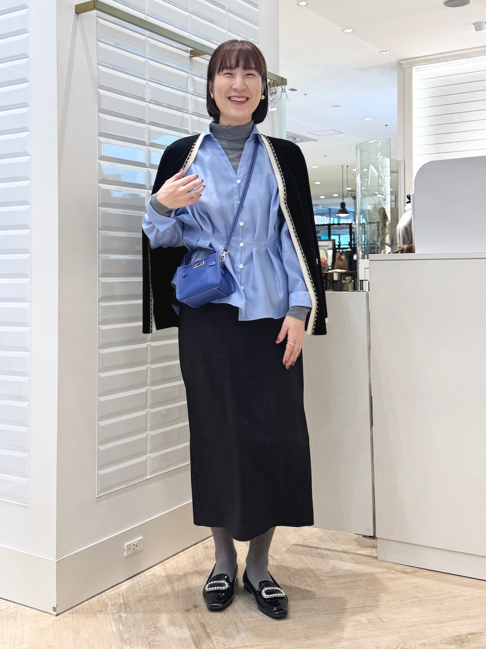 グレー系のニット/セーター、ベージュ系のスカート、ブルー系のショルダーバッグを着用したレディースの秋コーディネートの7枚目の写真