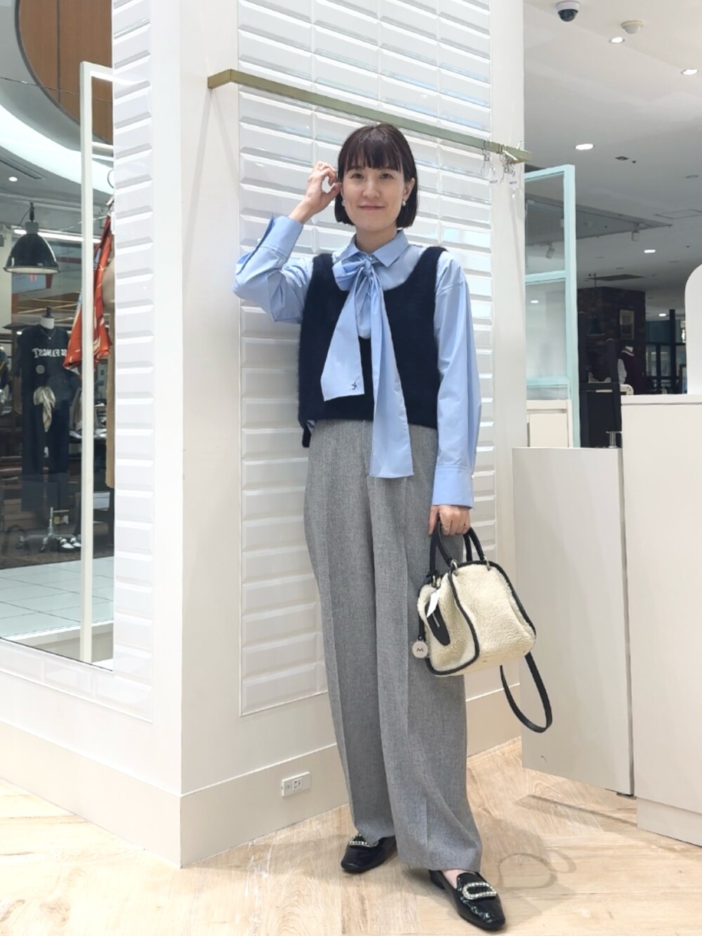 ホワイト系のボストンバッグ、ブルー系のベスト、ブルー系のシャツ/ブラウスを着用したレディースの秋コーディネートの3枚目の写真