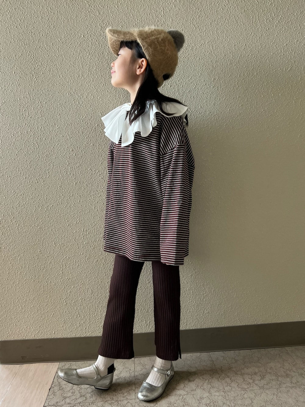 ブラウン系のTシャツ/カットソー、ブラウン系のパンツ、シルバー系のバレエシューズを着用したキッズの冬コーディネートの2枚目の写真