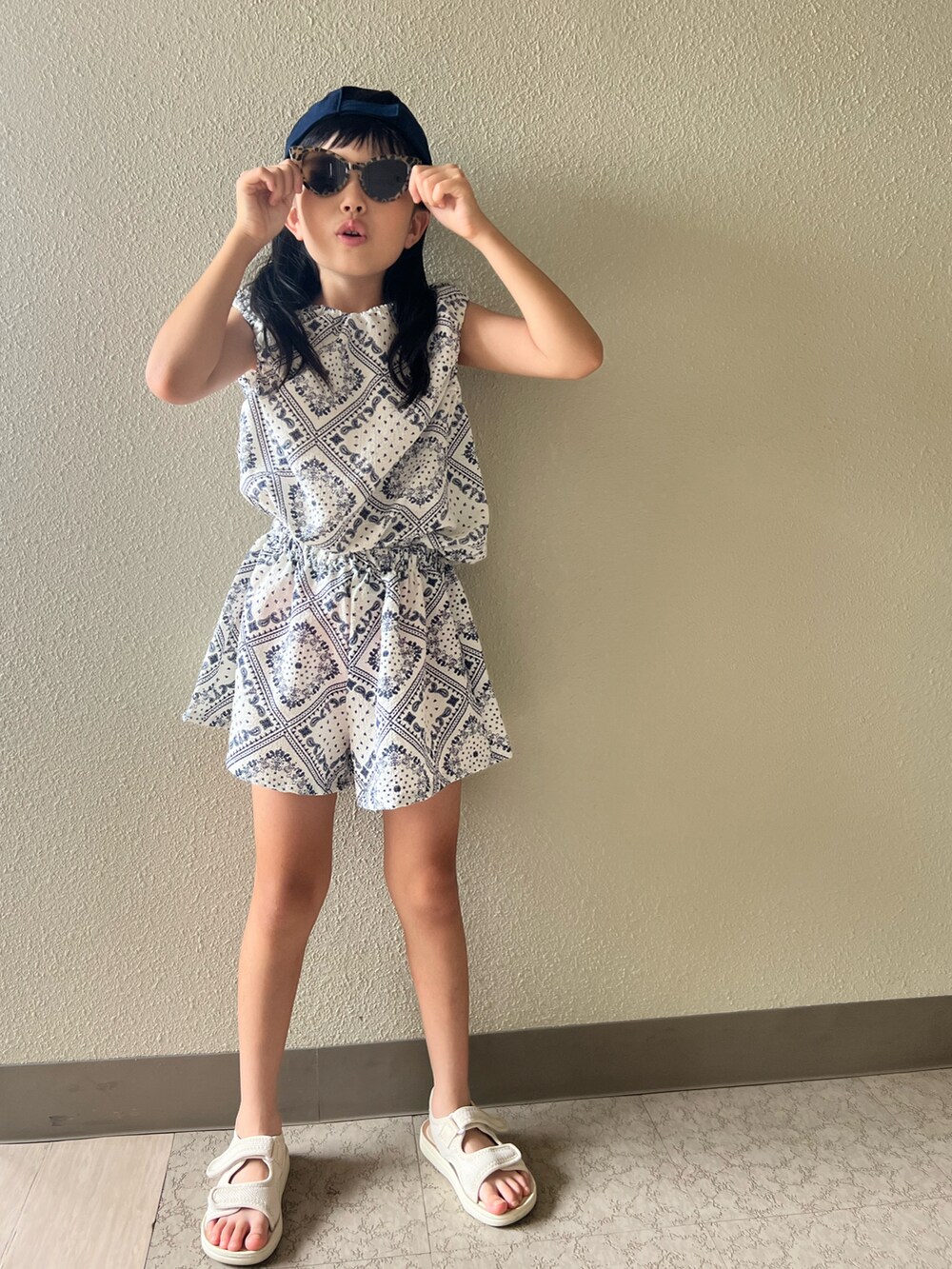 ベージュ系のサンダル、ホワイト系のスカート、ブラウン系のサングラスを着用したキッズの夏コーディネートの2枚目の写真