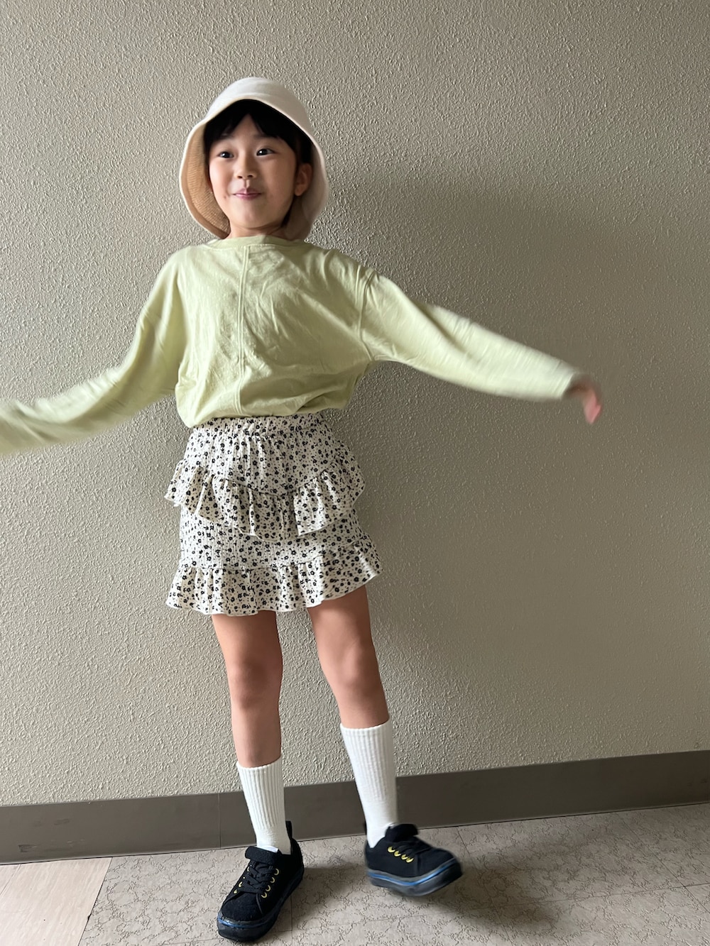 グリーン系のTシャツ/カットソー、ホワイト系のスカート、ブラック系のスニーカーを着用したキッズの春コーディネートの3枚目の写真