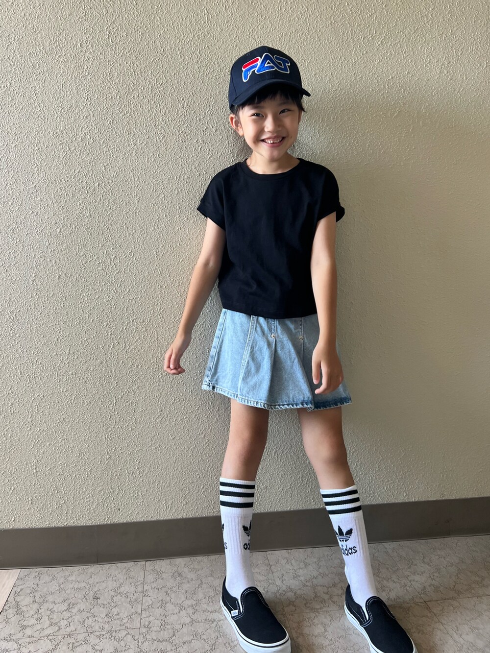 ブラック系のTシャツ/カットソー、ブルー系のデニムスカート、ブラック系のスニーカーを着用したキッズの夏コーディネートの2枚目の写真