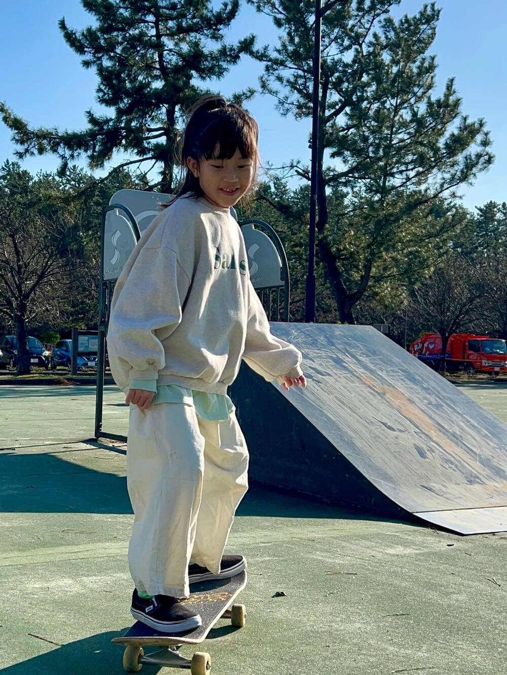 ベージュ系のスウェット、ホワイト系のカーゴパンツ、ブラック系のスニーカーを着用したキッズの冬コーディネートの2枚目の写真