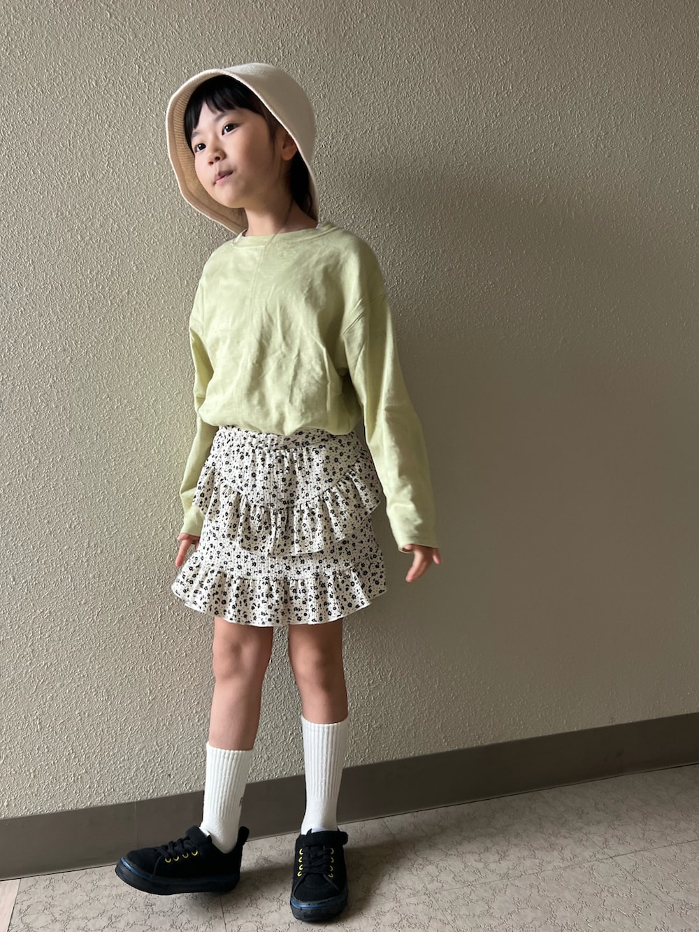 グリーン系のTシャツ/カットソー、ホワイト系のスカート、ブラック系のスニーカーを着用したキッズの春コーディネートの2枚目の写真