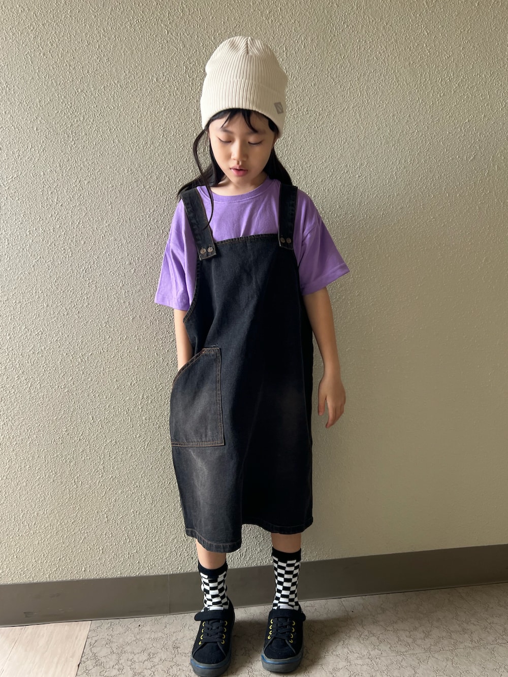 パープル系のTシャツ/カットソー、ブラック系のジャンパースカート、ブラック系のスニーカーを着用したキッズの春コーディネートの2枚目の写真