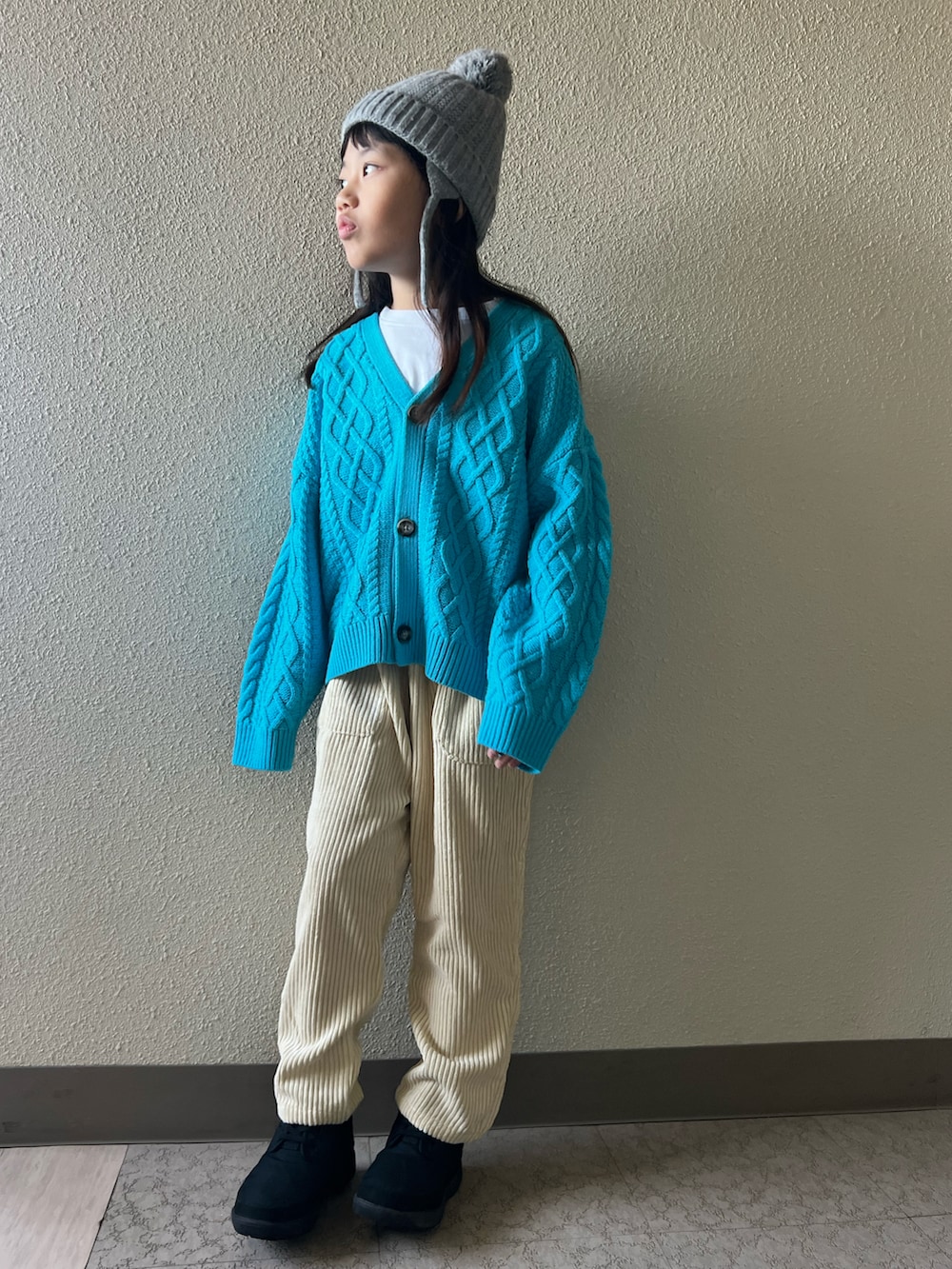 ブルー系のカーディガン/ボレロ、ホワイト系のその他パンツ、ブラック系のブーツを着用したキッズの冬コーディネートの3枚目の写真