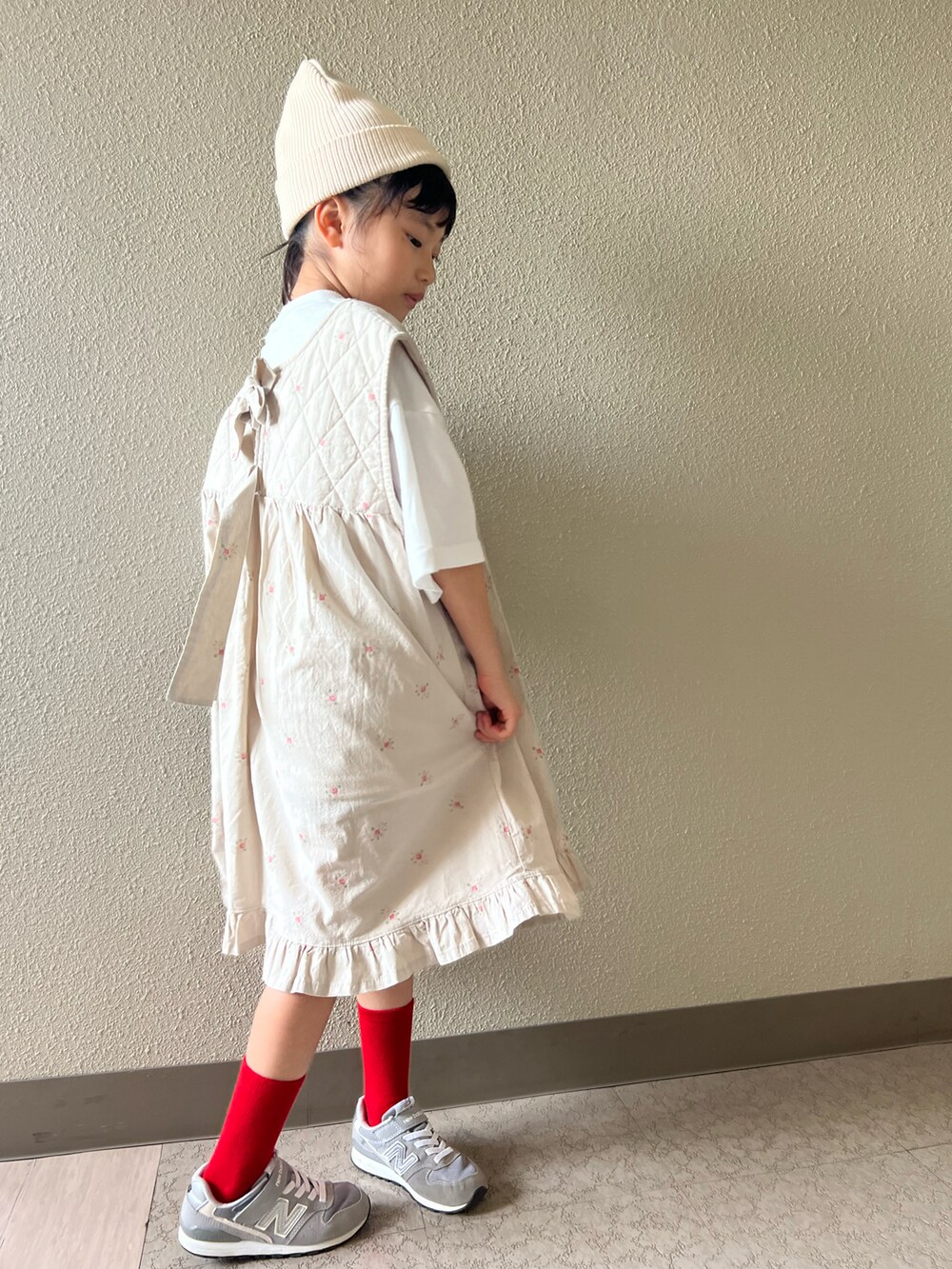 ベージュ系のワンピース、グレー系のスニーカー、ホワイト系のキャップを着用したキッズの春コーディネートの4枚目の写真