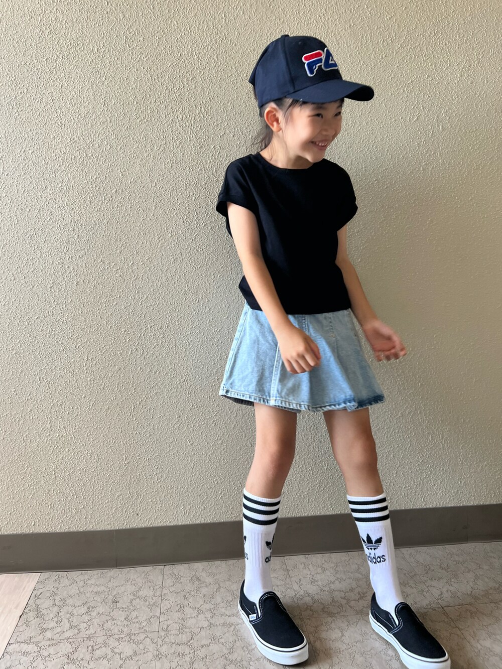 ブラック系のTシャツ/カットソー、ブルー系のデニムスカート、ブラック系のスニーカーを着用したキッズの夏コーディネートの3枚目の写真