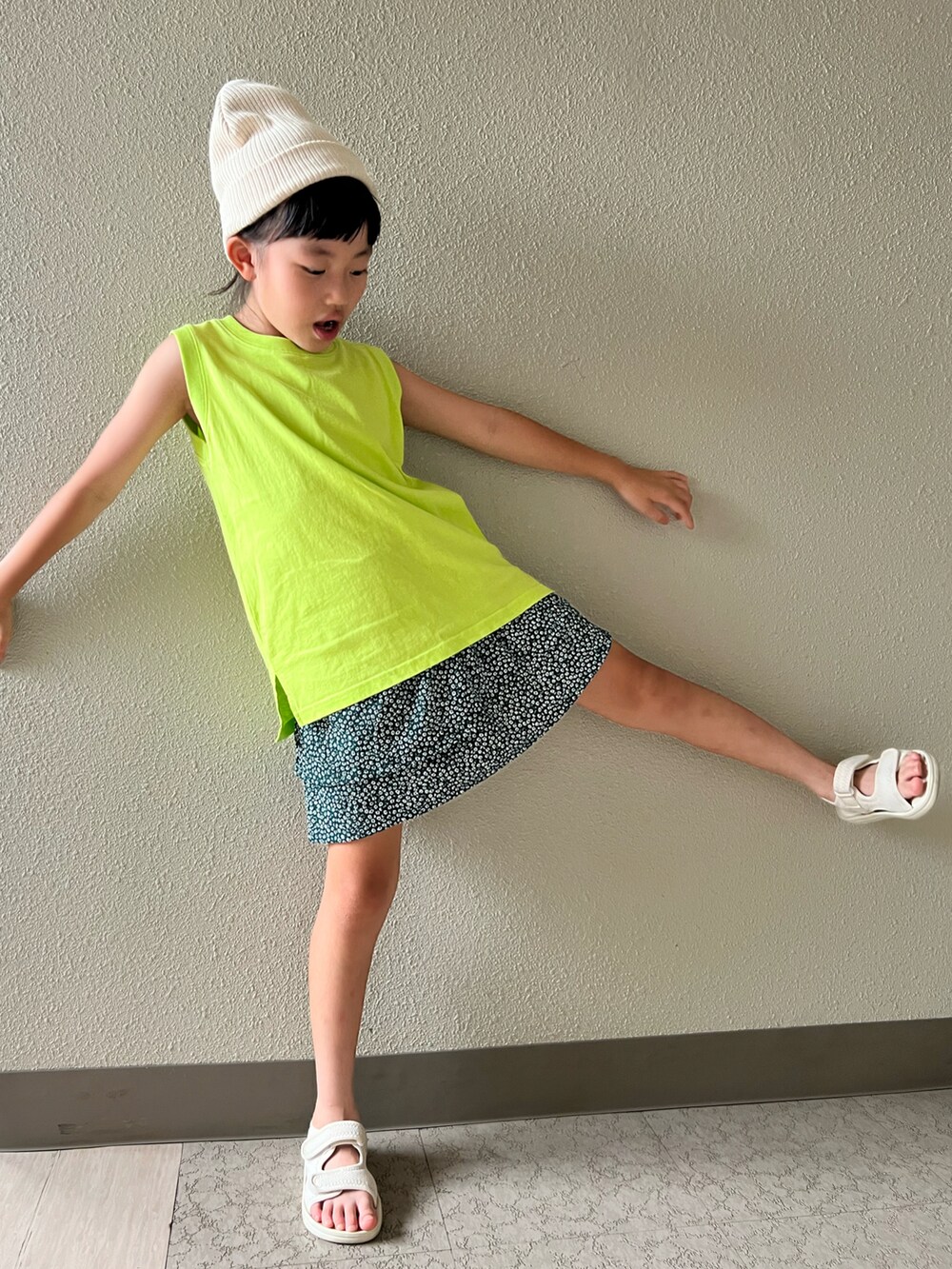 イエロー系のタンクトップ、グリーン系のスカート、ベージュ系のサンダルを着用したキッズの夏コーディネートの4枚目の写真
