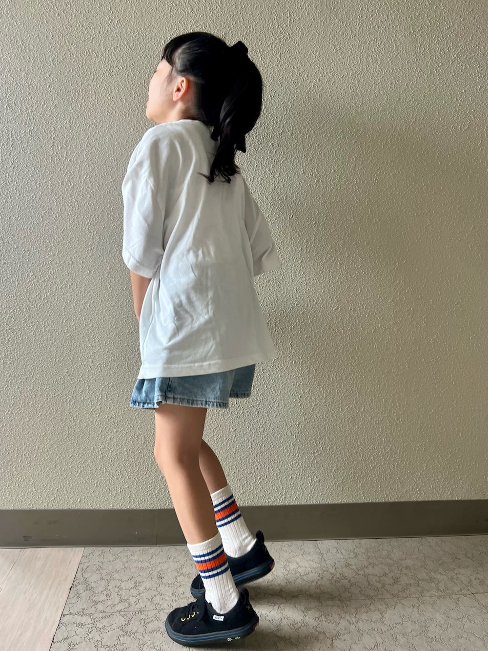 ホワイト系のTシャツ/カットソー、ブルー系のデニムスカート、ブラック系のスニーカーを着用したキッズの春コーディネートの3枚目の写真