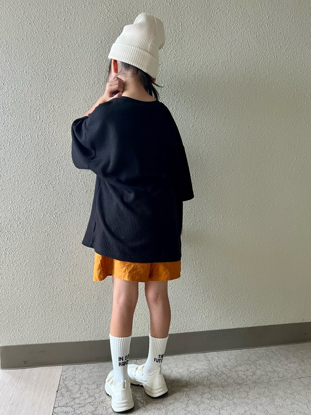 ブラック系のTシャツ/カットソー、オレンジ系のパンツ、ホワイト系のスニーカーを着用したキッズの春コーディネートの3枚目の写真