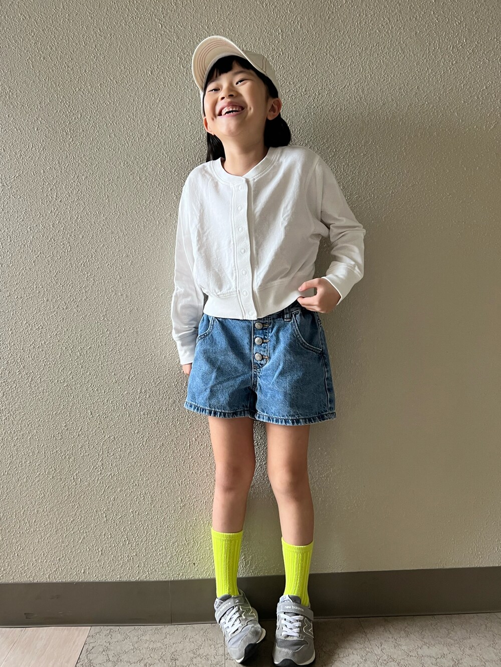 グレー系のスニーカー、ブルー系のデニムパンツ、ホワイト系のキャップを着用したキッズの春コーディネートの3枚目の写真