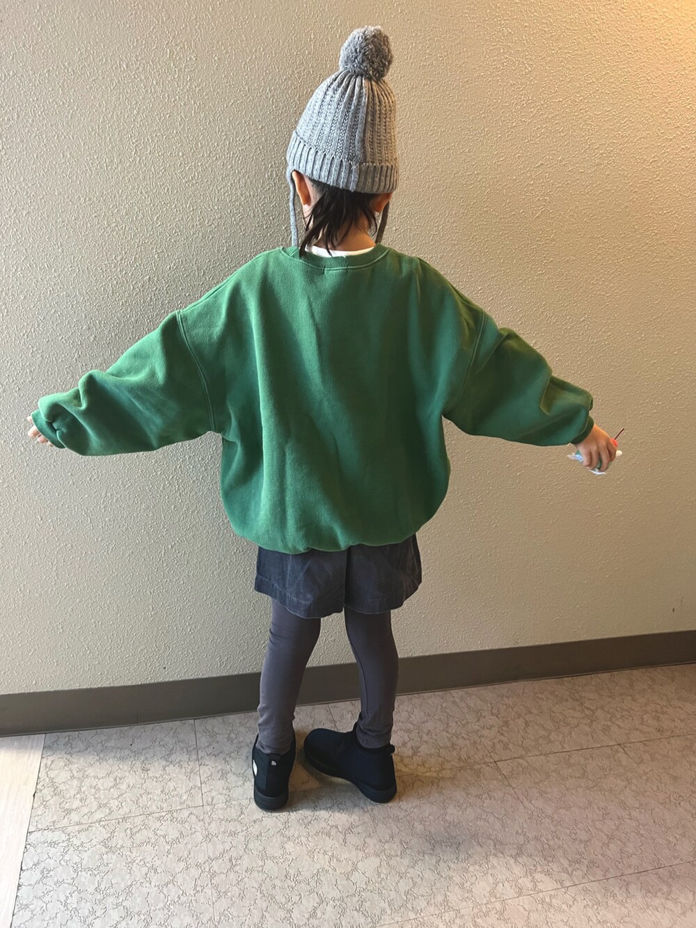 グリーン系のスウェット、グレー系のパンツ、ブラック系のブーツを着用したキッズの冬コーディネートの3枚目の写真