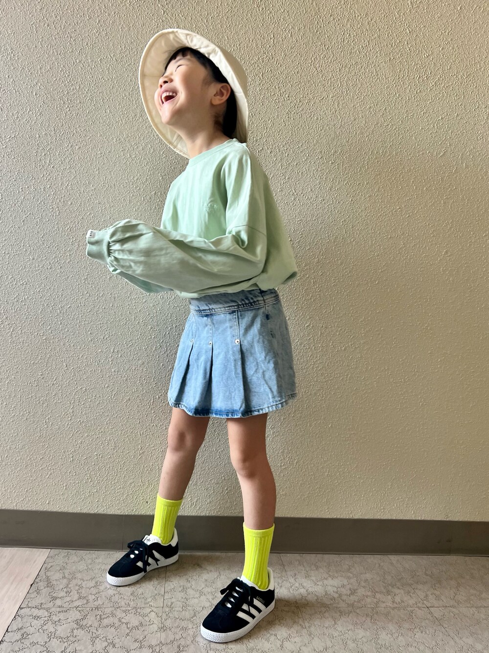 ブルー系のデニムスカート、グリーン系のTシャツ/カットソー、ブラック系のスニーカーを着用したキッズの春コーディネートの2枚目の写真