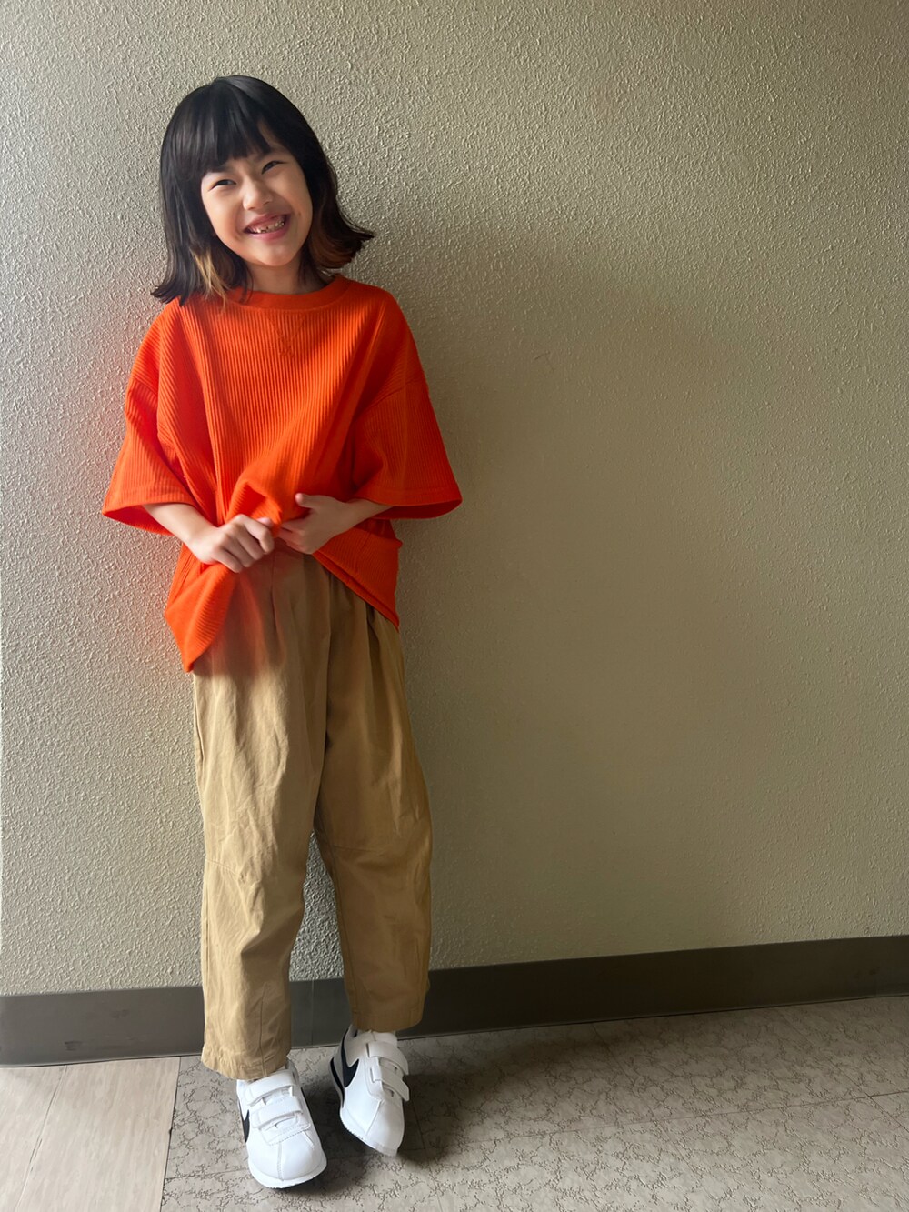 オレンジ系のTシャツ/カットソー、ホワイト系のカーゴパンツ、ホワイト系のスニーカーを着用したキッズの春コーディネートの3枚目の写真