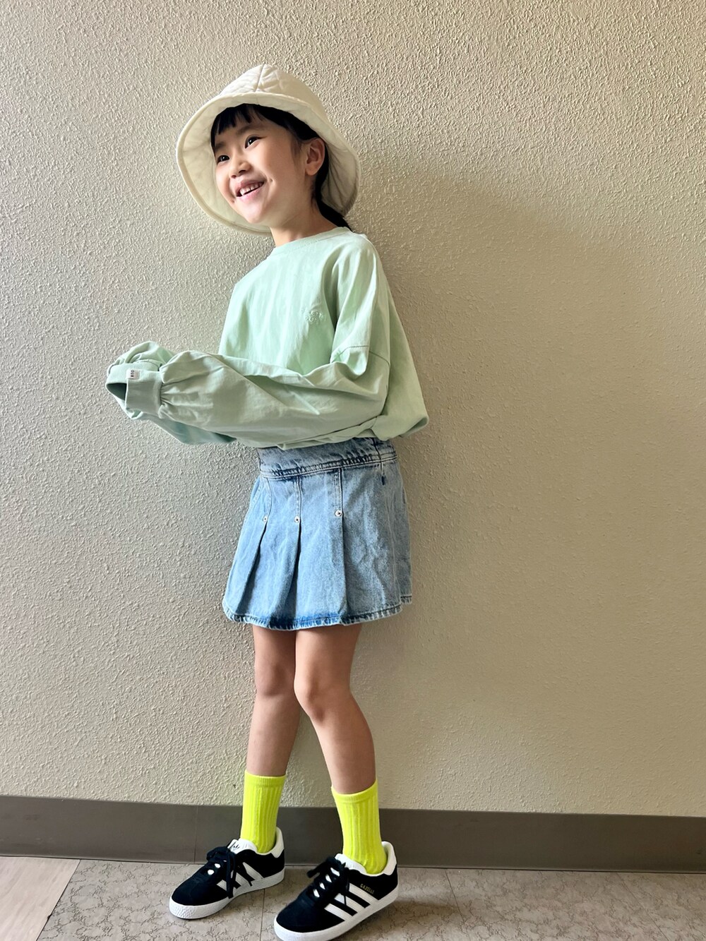 ブルー系のデニムスカート、グリーン系のTシャツ/カットソー、ブラック系のスニーカーを着用したキッズの春コーディネートの3枚目の写真