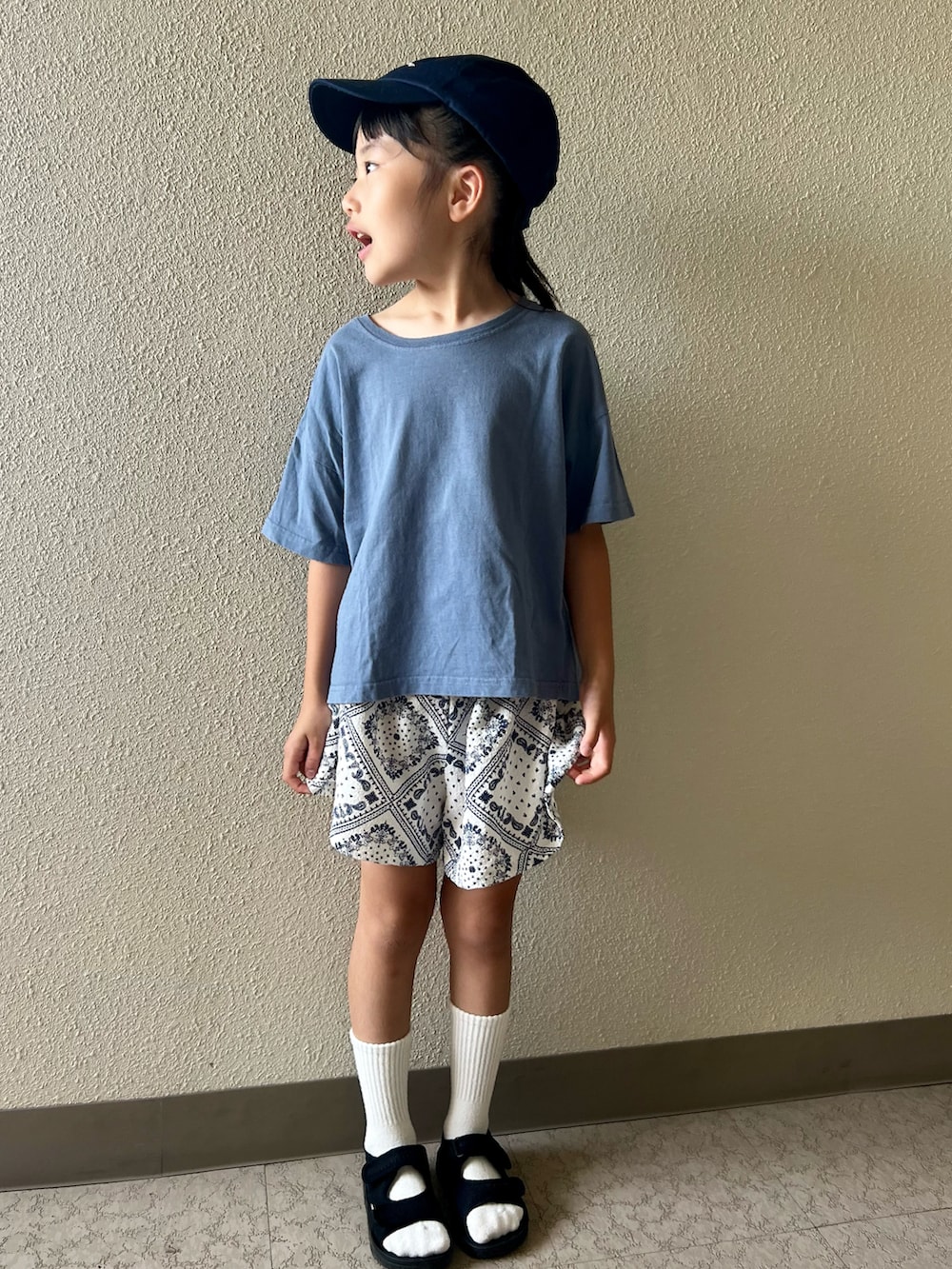 ブルー系のTシャツ/カットソー、ホワイト系のスカート、ブラック系のサンダルを着用したキッズの春コーディネートの2枚目の写真