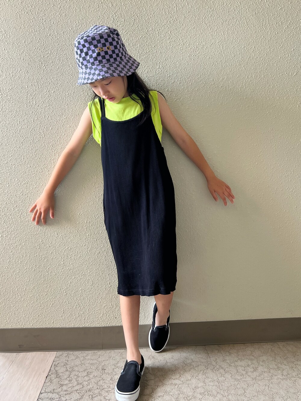 イエロー系のタンクトップ、ブラック系のスニーカー、ブラック系のワンピースを着用したキッズの夏コーディネートの2枚目の写真