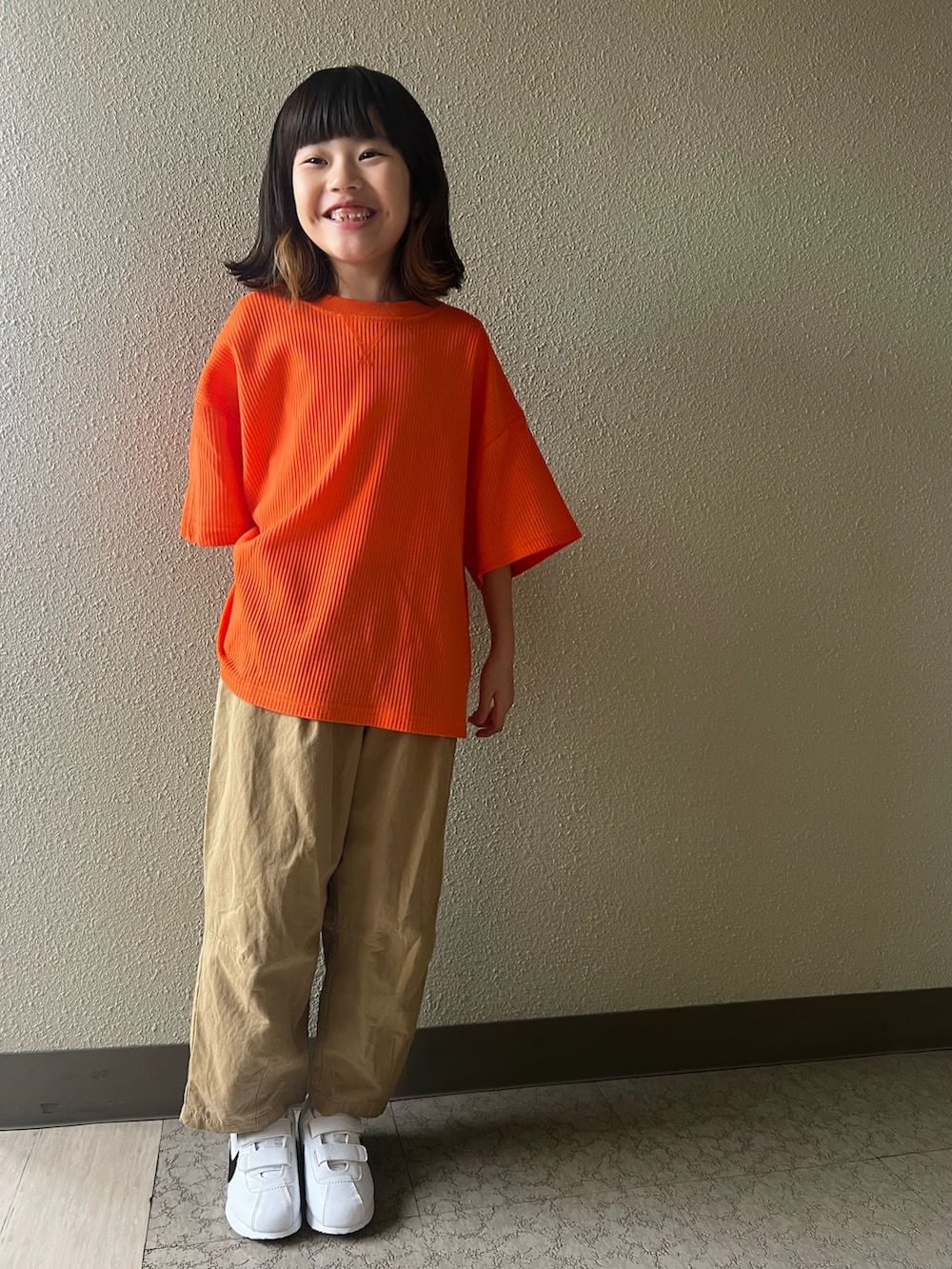 オレンジ系のTシャツ/カットソー、ホワイト系のカーゴパンツ、ホワイト系のスニーカーを着用したキッズの春コーディネートの2枚目の写真