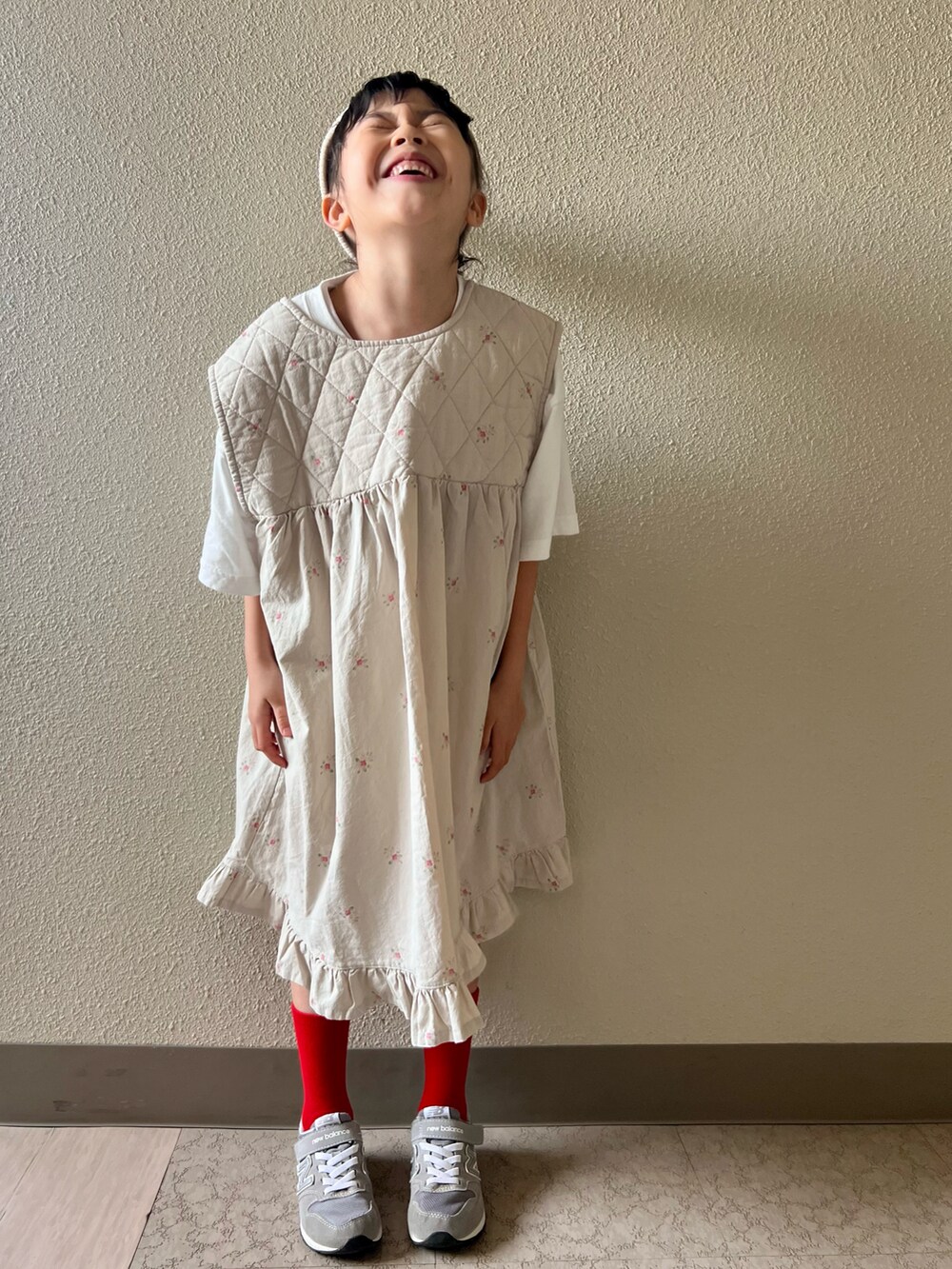 ベージュ系のワンピース、グレー系のスニーカー、ホワイト系のキャップを着用したキッズの春コーディネートの3枚目の写真