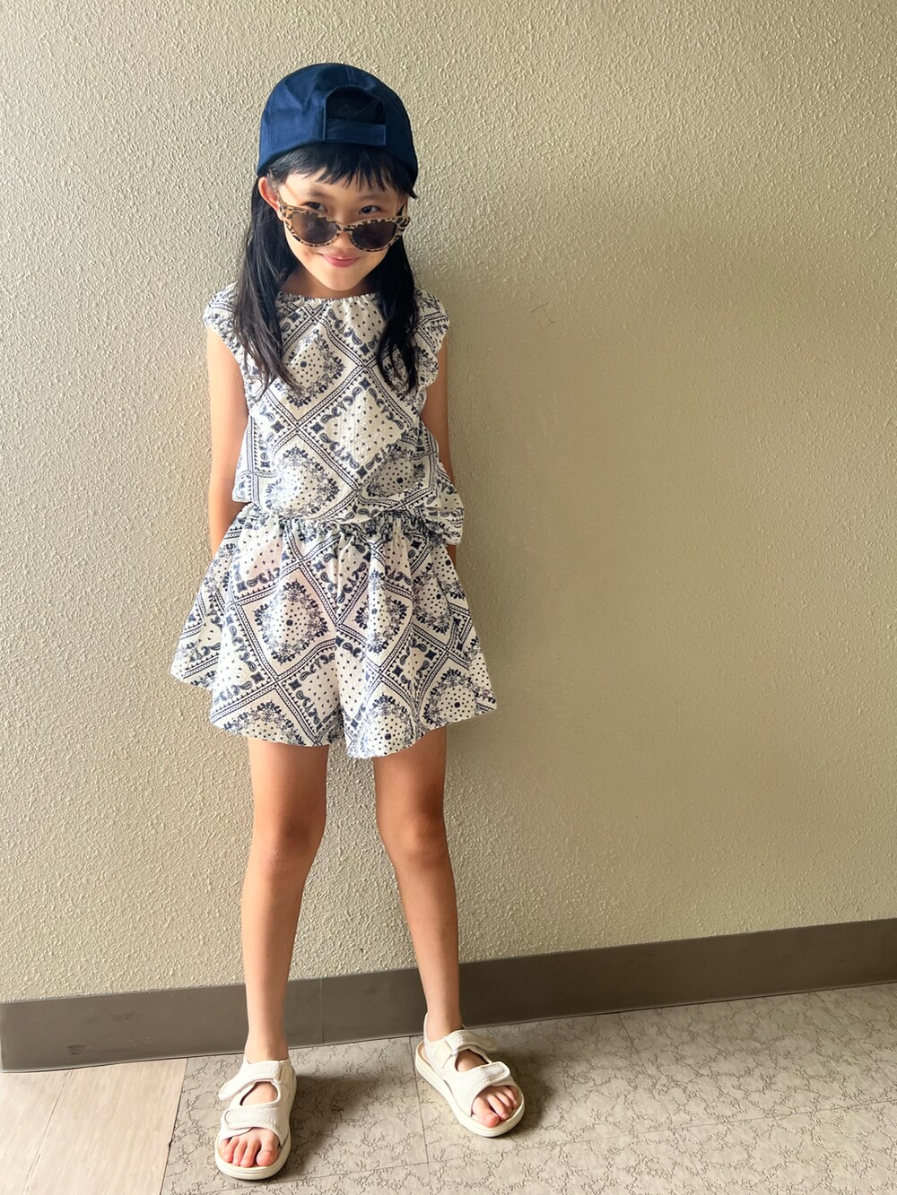 ベージュ系のサンダル、ホワイト系のスカート、ブラウン系のサングラスを着用したキッズの夏コーディネートの3枚目の写真