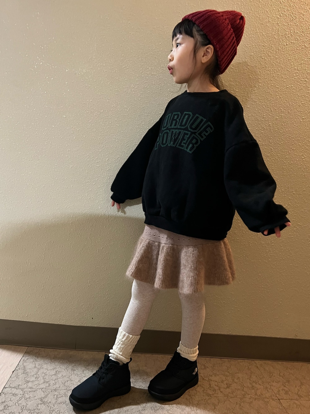 ブラック系のスウェット、ベージュ系のスカート、ブラック系のブーツを着用したキッズの冬コーディネートの2枚目の写真