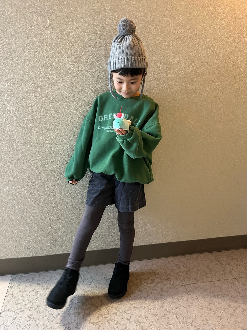 グリーン系のスウェット、グレー系のパンツ、ブラック系のブーツを着用したキッズの冬コーディネートの2枚目の写真