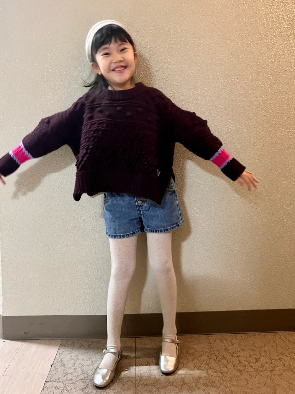 ブラウン系のニット/セーター、ブルー系のデニムパンツ、シルバー系のバレエシューズを着用したキッズの冬コーディネートの3枚目の写真