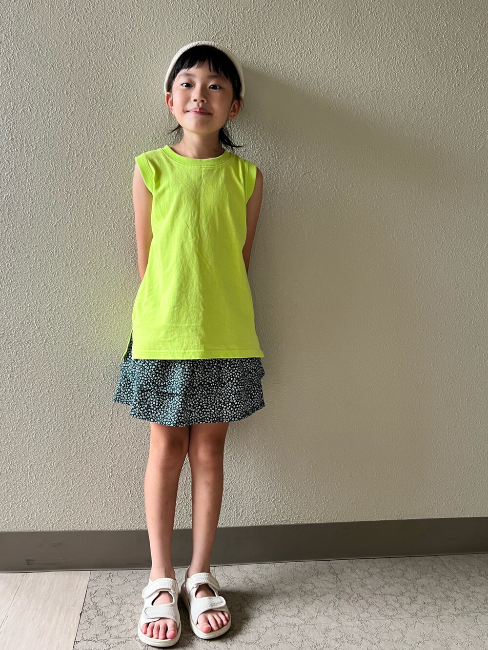 イエロー系のタンクトップ、グリーン系のスカート、ベージュ系のサンダルを着用したキッズの夏コーディネートの2枚目の写真