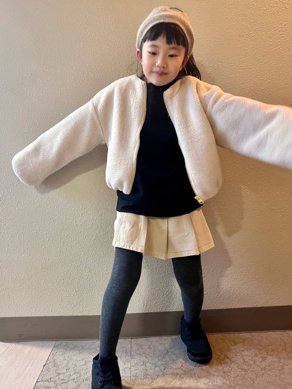 ホワイト系のブルゾン、ブラック系のスウェット、ベージュ系のスカートを着用したキッズの冬コーディネートの2枚目の写真