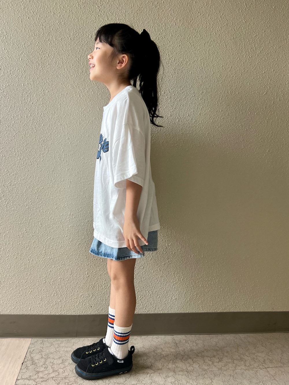 ホワイト系のTシャツ/カットソー、ブルー系のデニムスカート、ブラック系のスニーカーを着用したキッズの春コーディネートの2枚目の写真