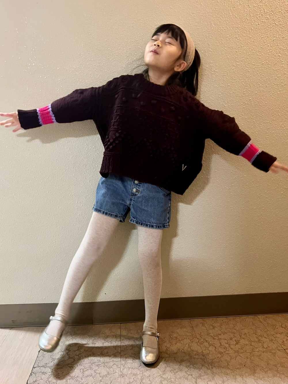 ブラウン系のニット/セーター、ブルー系のデニムパンツ、シルバー系のバレエシューズを着用したキッズの冬コーディネートの2枚目の写真