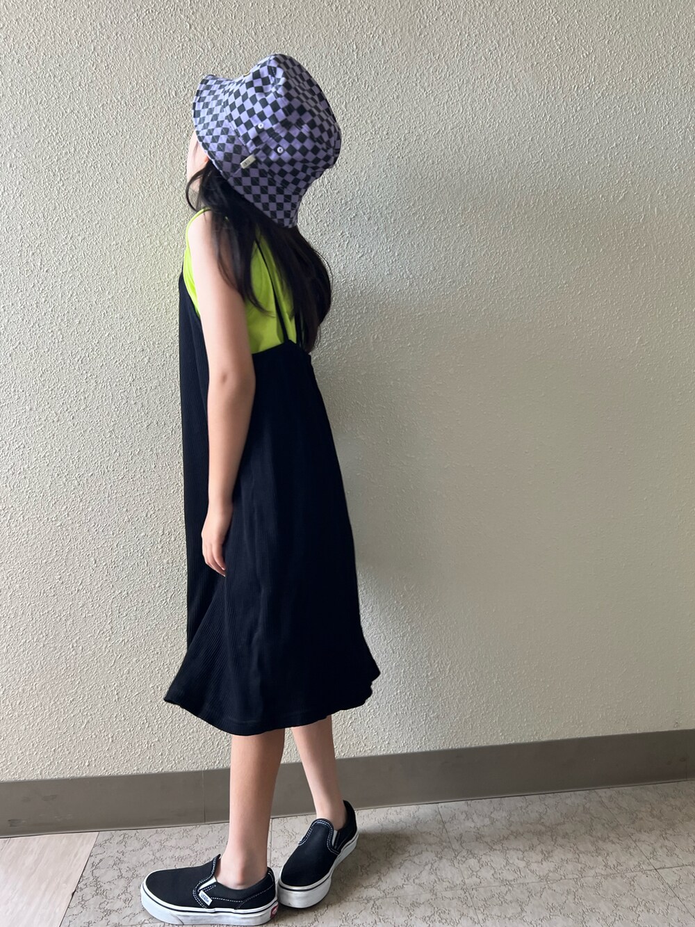 イエロー系のタンクトップ、ブラック系のスニーカー、ブラック系のワンピースを着用したキッズの夏コーディネートの4枚目の写真