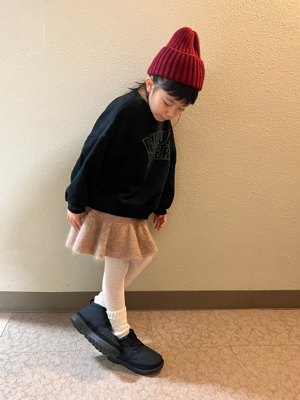 ブラック系のスウェット、ベージュ系のスカート、ブラック系のブーツを着用したキッズの冬コーディネートの3枚目の写真