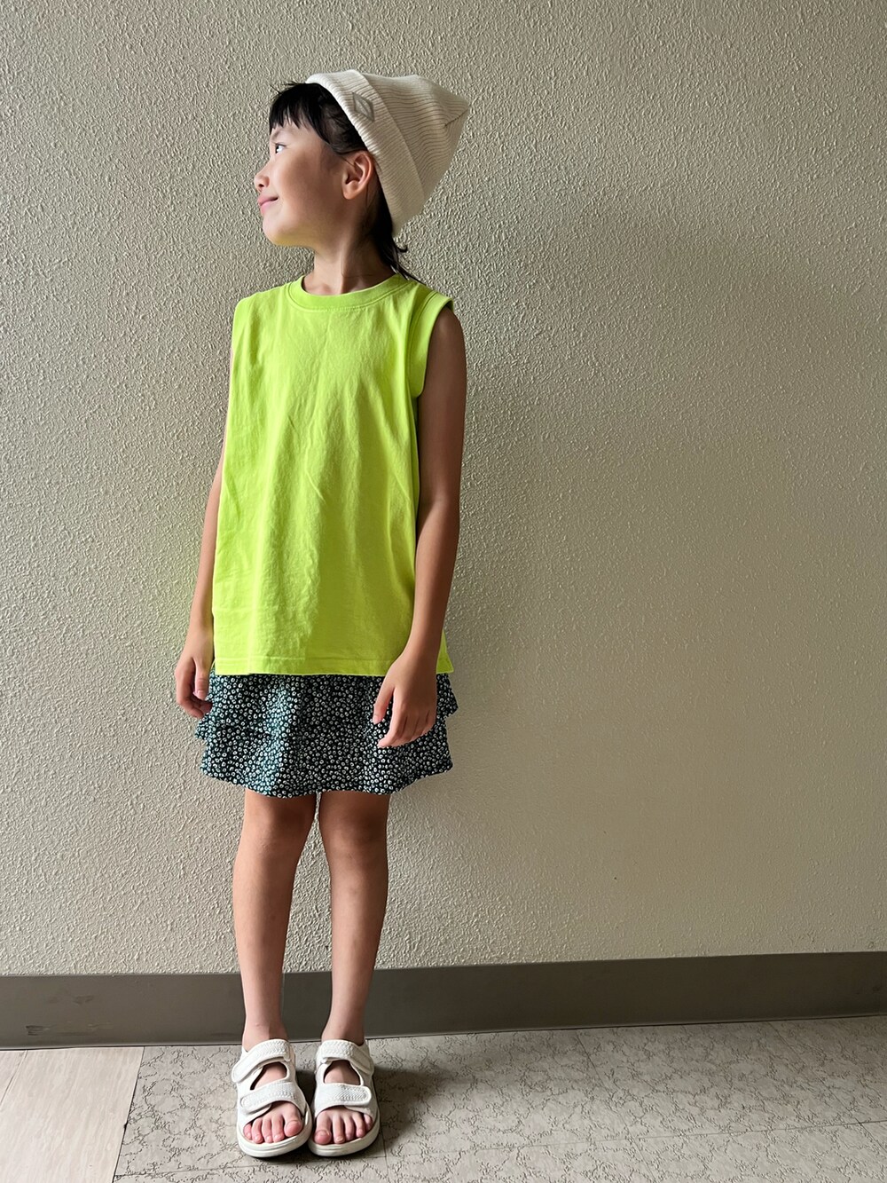 イエロー系のタンクトップ、グリーン系のスカート、ベージュ系のサンダルを着用したキッズの夏コーディネートの3枚目の写真