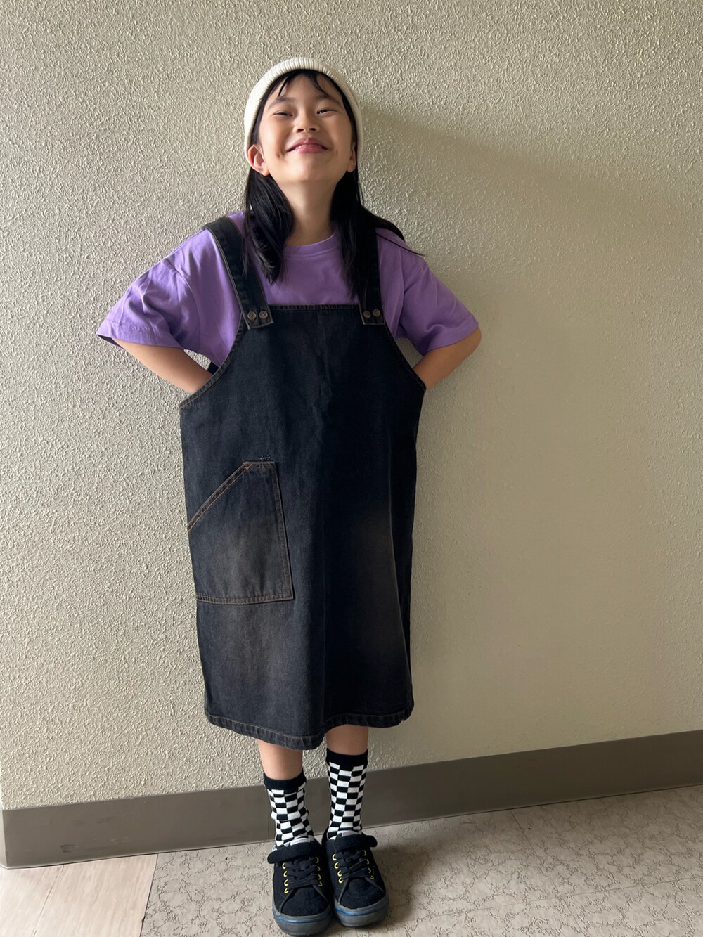 パープル系のTシャツ/カットソー、ブラック系のジャンパースカート、ブラック系のスニーカーを着用したキッズの春コーディネートの4枚目の写真