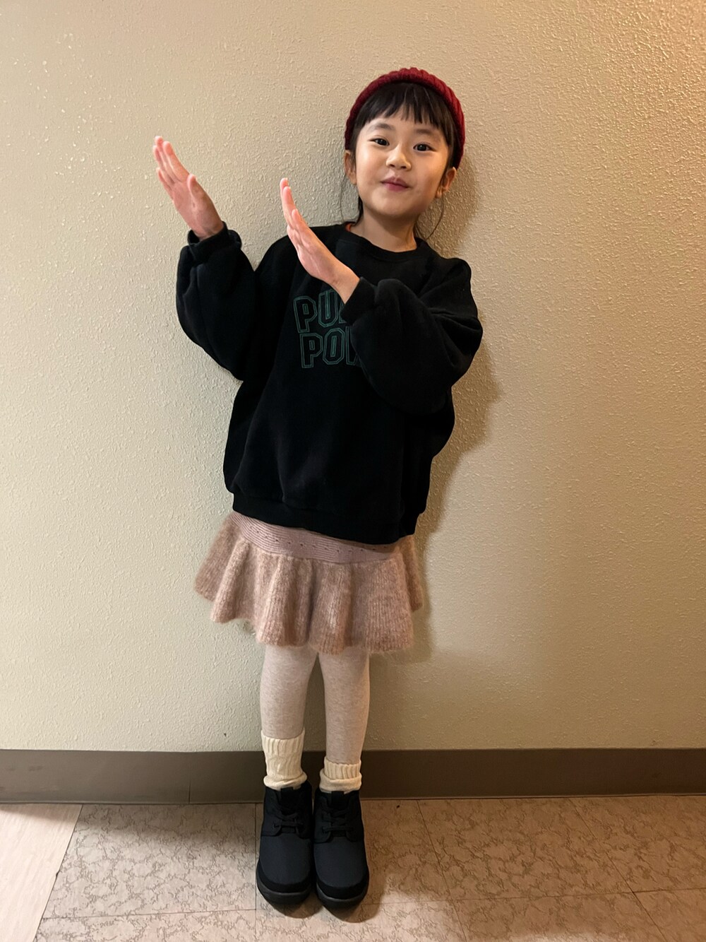 ブラック系のスウェット、ベージュ系のスカート、ブラック系のブーツを着用したキッズの冬コーディネートの4枚目の写真