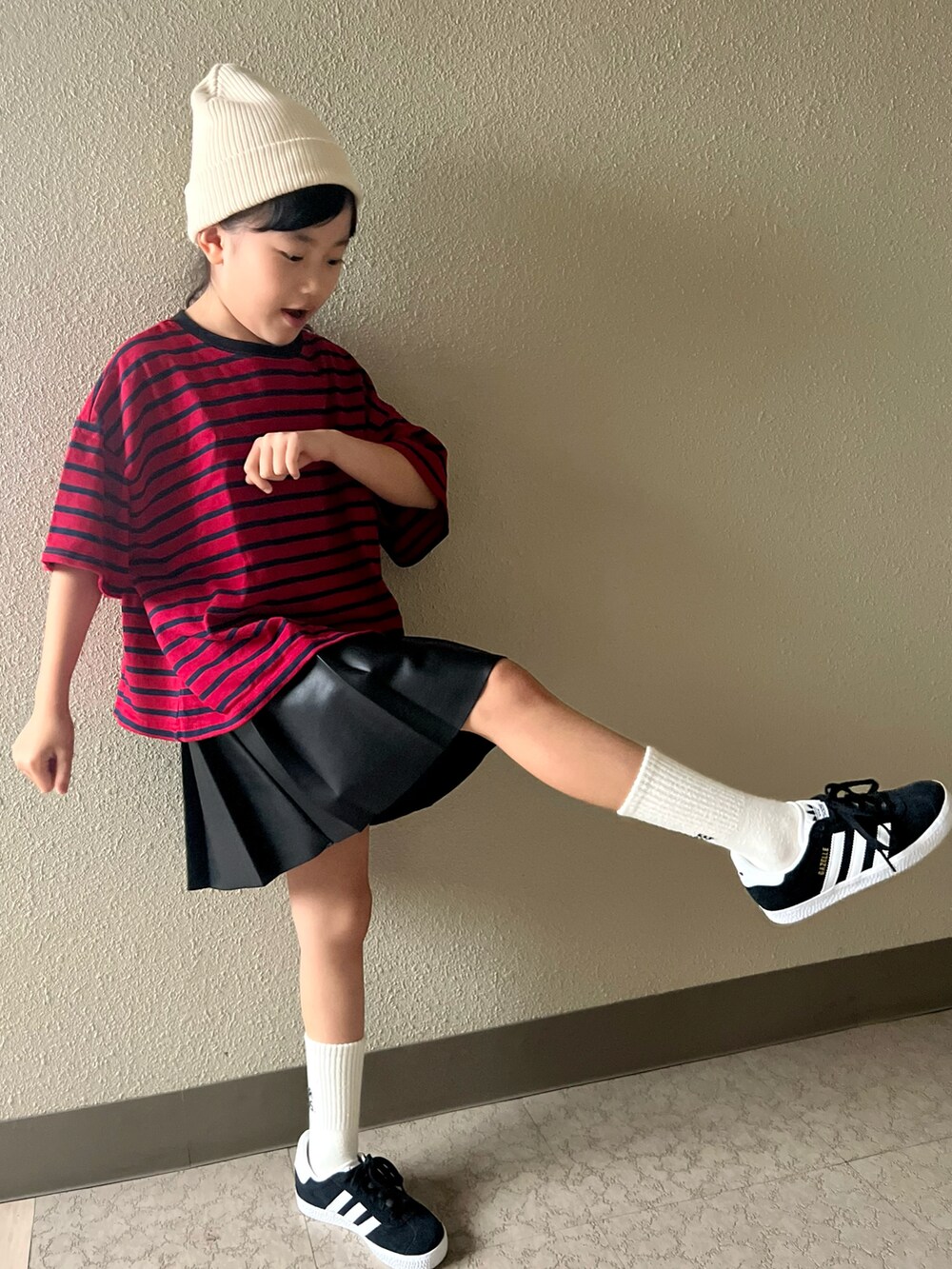 レッド系のTシャツ/カットソー、ブラック系のスカート、ブラック系のスニーカーを着用したキッズの春コーディネートの2枚目の写真