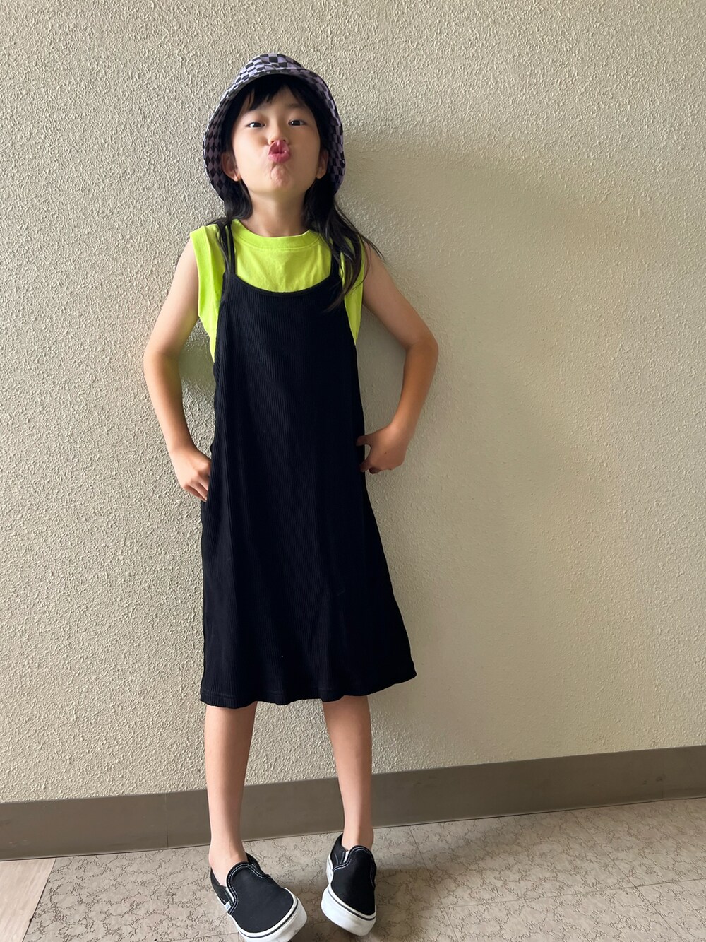 イエロー系のタンクトップ、ブラック系のスニーカー、ブラック系のワンピースを着用したキッズの夏コーディネートの3枚目の写真