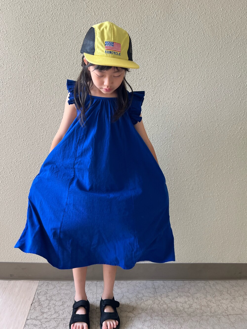 ブルー系のワンピース、ブラック系のサンダルを着用したキッズの夏コーディネートの2枚目の写真
